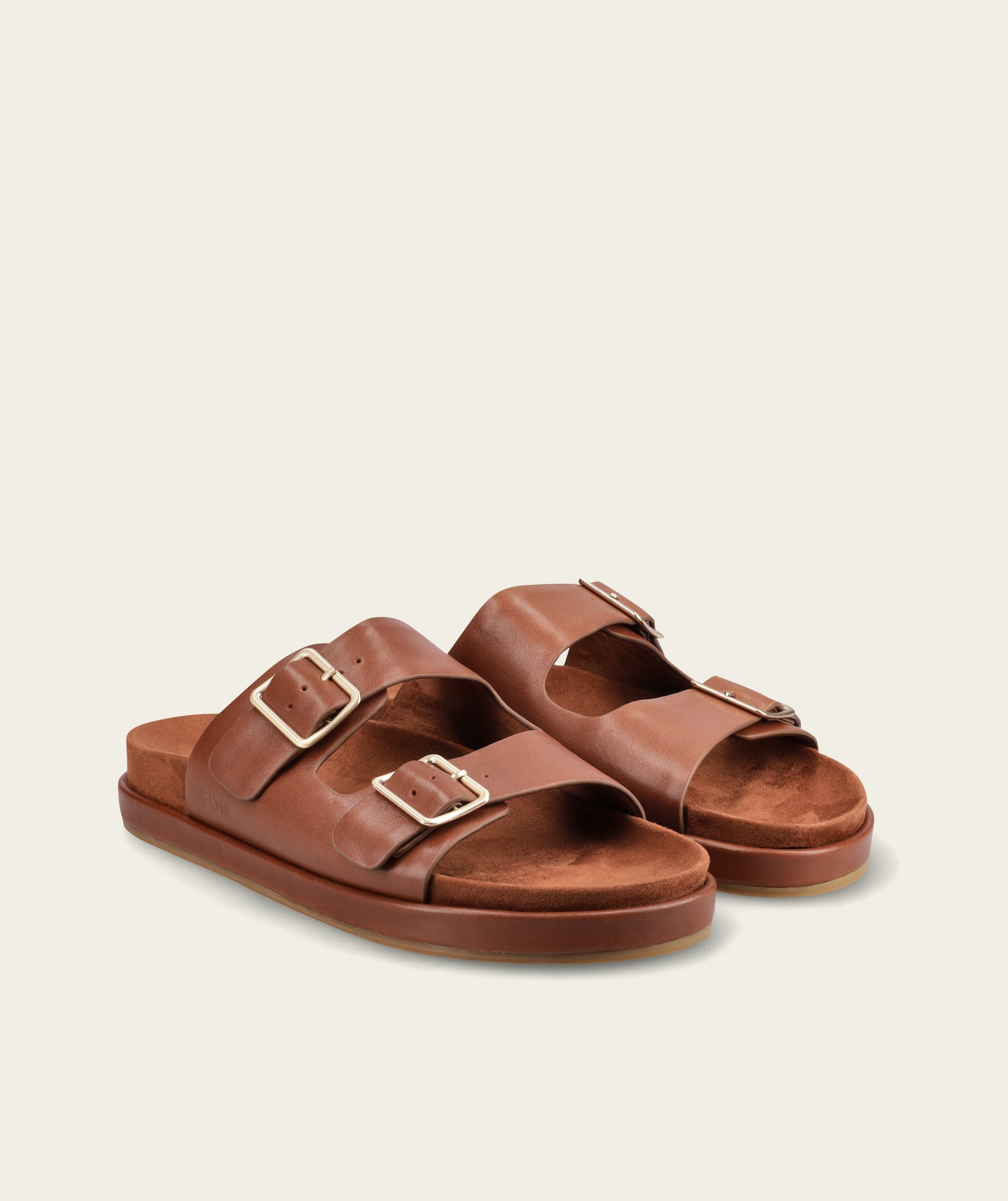 FOM Dani leather slide sandal in ox choc, front angled view of the pair showing twin gold buckles and suede footbed